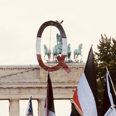 Vor dem Brandenburger Tor tragen Demonstrant:innen Reichsflaggen und den Buchstaben Q in Reichsflaggen-Optik. Das Q steht für "QAnon".