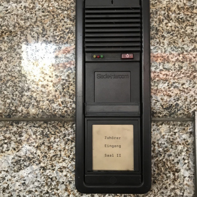 Klingelschild mit Beschriftung "Zuhörer Eingang Saal II"
